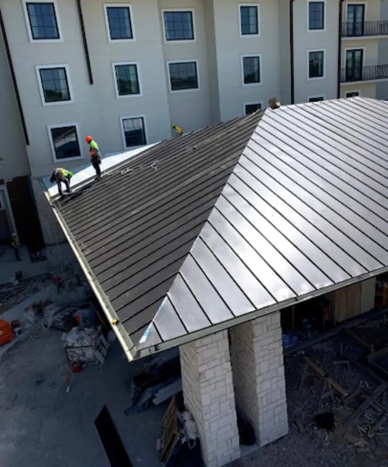 Crew installing standing seam metal roof panels on a commercial project in Blue Ash
